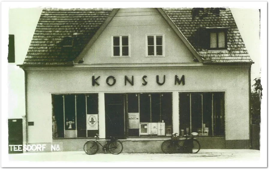 Altes Schwarzweißfoto: das Haus in Teesdorf mit der Aufschrift Konsum, zwei Fahrräder davor