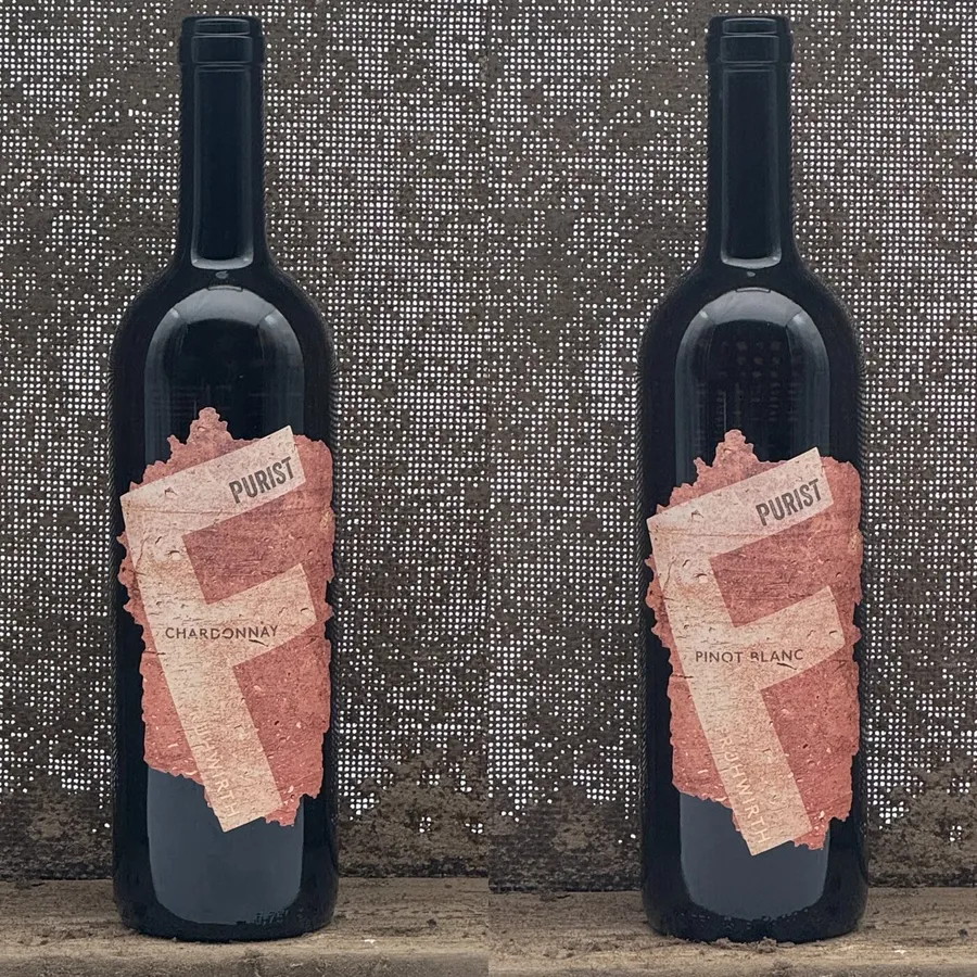 Zwei Flaschen Purist, Chardonnay und Pinot Blanc, vor einer Steinmauer