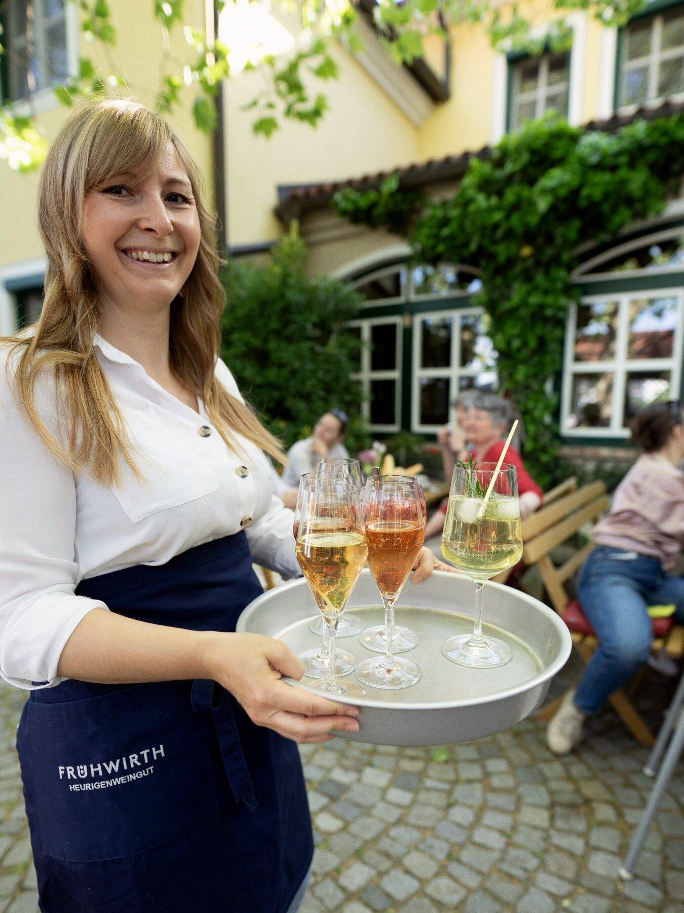 Service bringt ein Tablett mit Spritzern in den Gastgarten