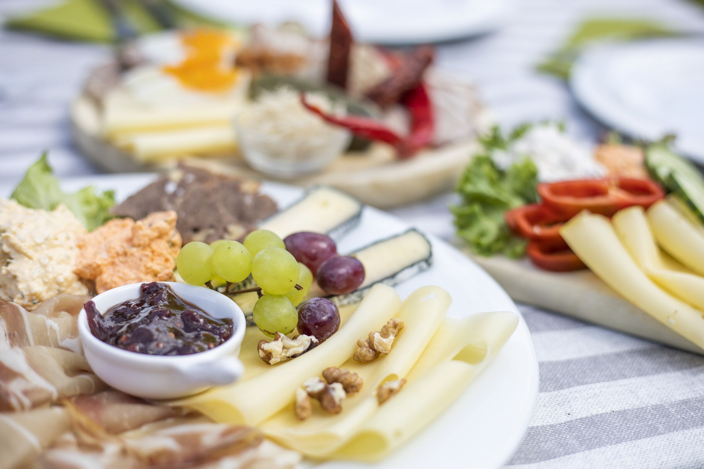 Mehrere Platten mit Käse, Aufstrichen, Trauben, Nüssen und Gemüse