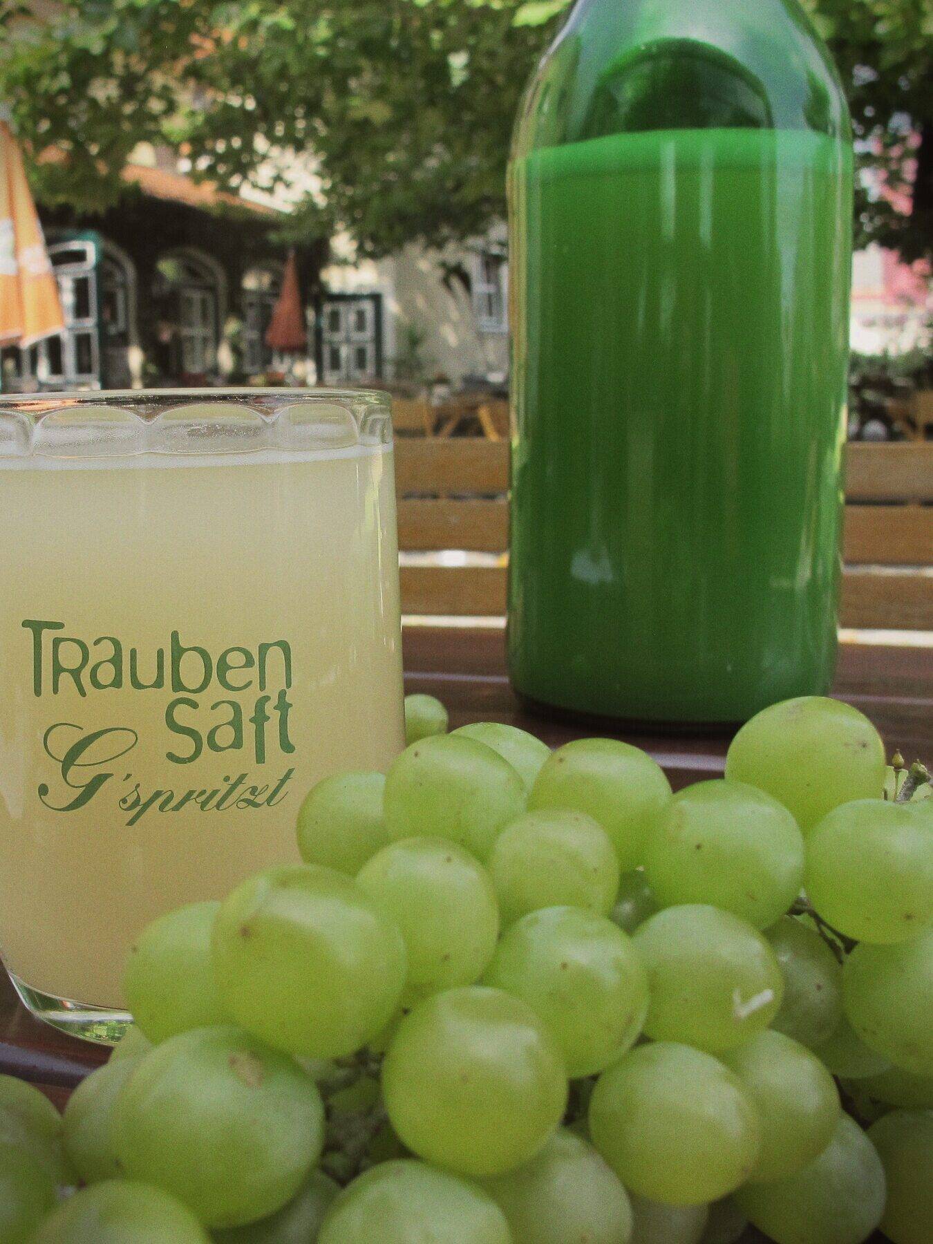 Ein Krug Traubensaft, eine 2-Liter-Flasche Sturm und frische Trauben auf dem Tisch im Gastgarten