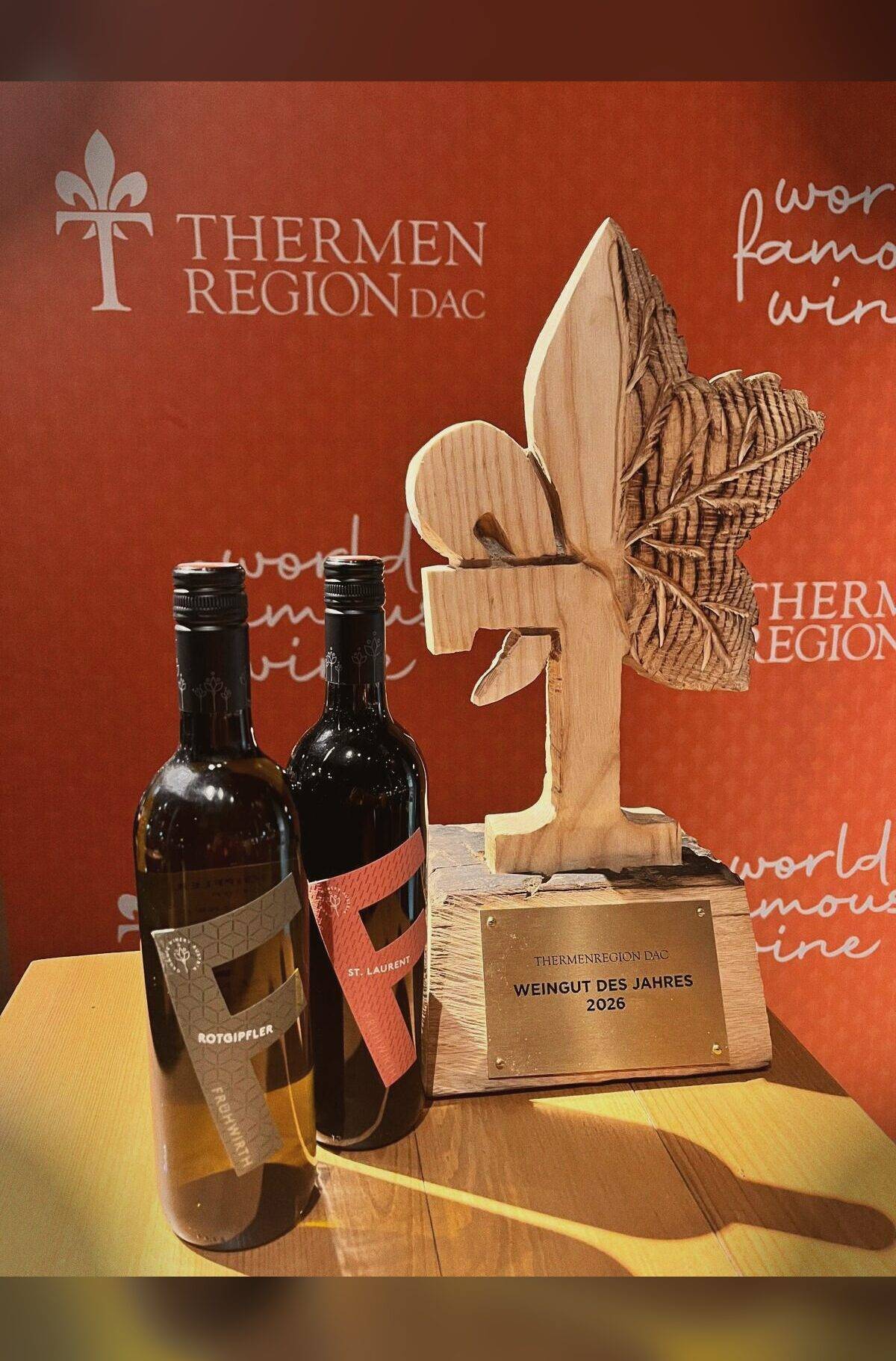 Die Holztrophäe Weingut des Jahres 2026 der Thermenregion DAC mit zwei Flaschen
